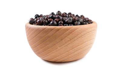 juniper berries in wooden bowl isolated on white background. Spices and food ingredients.