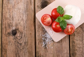 fresh tomatoes with mozzarella cheese and basil  on a rustic wooden table - healthy breakfast - top view