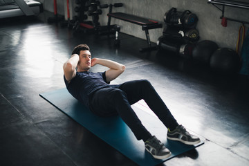 Young man caucasian Being exercised by a sit-up on yoga mat. He wears sportswear. Fitness in the gym concept.