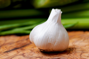 Organic Raw Whole Garlic bulb placed on natural olive wood. Allium sativum.