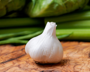 Organic Raw Whole Garlic bulb placed on natural olive wood. Allium sativum.