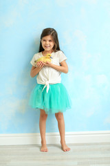 A cute Asian girl in a blue skirt is holding a yellow duckling . Easter