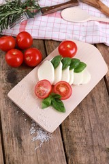 tomato mozzarella - fresh tomatoes with mozzarella cheese and basil  on a rustic wooden table