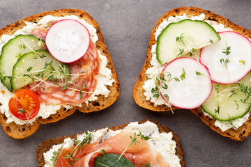 Sandwich with cereals bread and salami on dark marble background.