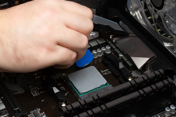 Fototapeta na wymiar Work to collect a personal computer. Male hand applies thermal grease to the processor.