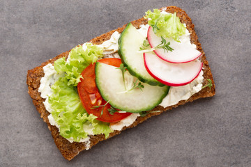 Sandwich with cereals bread and salami on dark marble background.