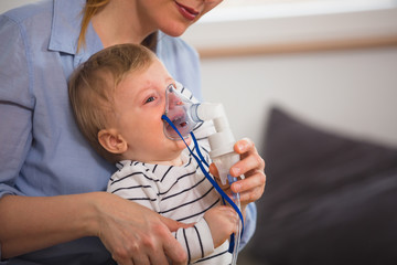 little boy crying while taking inhalation with nebuliser