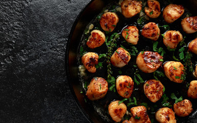 Scallops seared in garlic and parsley butter served in cast iron skillet