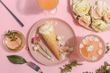 Light pink set of dishes on the table. Delicate rosebuds of pastel colors and petals on a plate and...