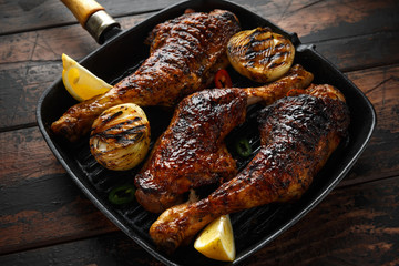 Grilled chicken legs with lemon in cast iron skillet