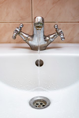 Vertical image of a tap with water flowing slowly during a period of scarcityTap with Water Flowing Slowly