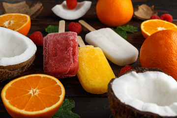 Homemade Coconut, Orange, raspberry popsicles, ice lolly, on wooden table. Summer food.