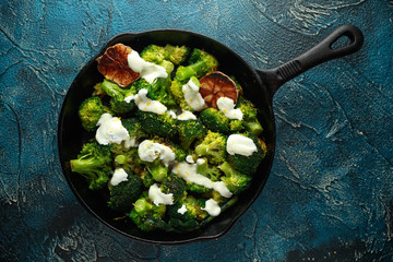 Fried broccoli with garlic yogurt and lemon zest in cast iron skillet, frying pan