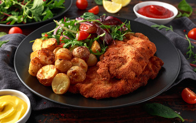 Homemade breaded pork schnitzel with roast potato and vegetables