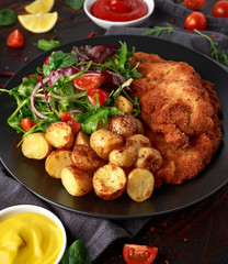 Homemade breaded pork schnitzel with roast potato and vegetables