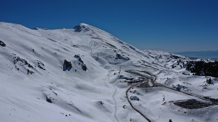 Fototapeta na wymiar Aerial drone photo of iconic snowed mountain of Parnassus with popular ski resort covered up in snow and unique nature, Voiotia, Greece