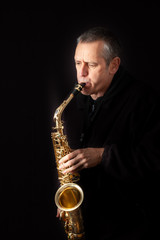 A Musician playing jazz music on his saxophone, on black background