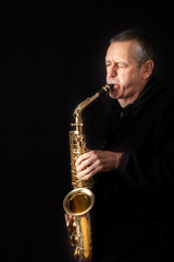 Fototapeta premium A Musician playing jazz music on his saxophone, on black background