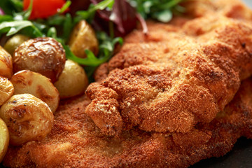 Homemade breaded pork schnitzel with roast potato and vegetables