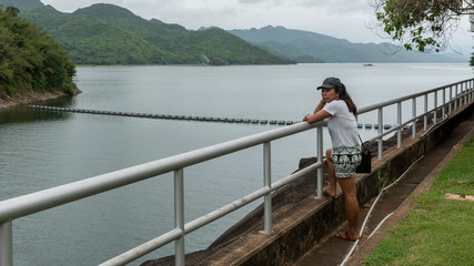 Fototapeta na wymiar Asian woman leaning on railing looking at resevoir