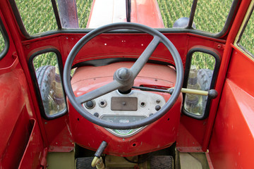 The tractor rides in the field, looking from the inside. The interior of the red retro tractor with...