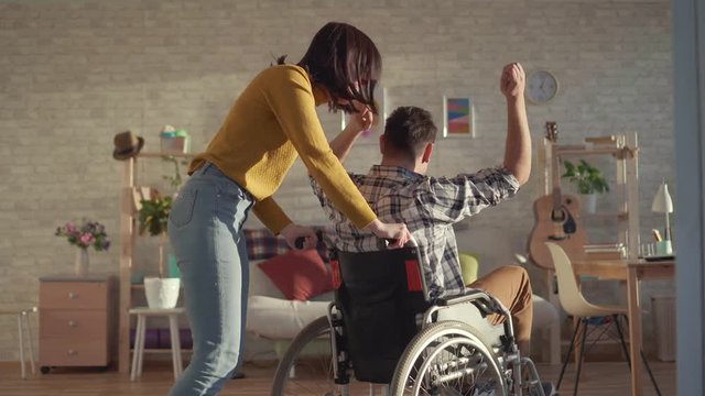 Disabled man in a wheelchair expressive dancing with a young woman