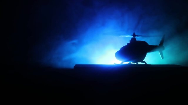 Silhouette of military helicopter ready to fly from conflict zone. Decorated night footage with helicopter starting in desert with foggy toned backlit. Selective focus. War concept