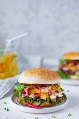 Homemade fresh chicken burger with bacon on gray plate on white background with lemonade, Fast food at summer time
