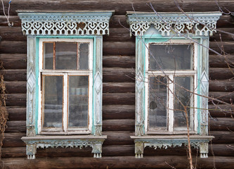 Facade of old wooden house. Two windows with decorative wooden carving frame. Russian traditional folk style. Front view close up