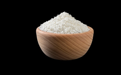 coconut shreds in wooden bowl isolated on black background. Spices and food ingredients.