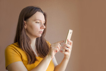technology concept - smiling young woman in blank yellow t-shirt using smartphone