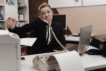 Office worker stressed. Overworked concept. Angry furious businesswoman beating boken printer.