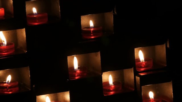 Beautiful red church candles for prayers in special niches in a catholic temple on a black background