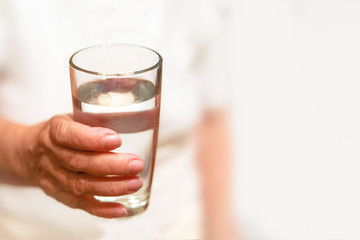 glass of water in the hands of my grandmother, old hands hold a glass of water