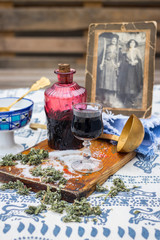 Dark red cherry liquor in vintage glass decanter or pitcher and small shot glass. Thick and lingering alcohol drink in glass bottle with sugar, herbs, wine and spices. On table.