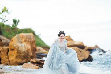 Fototapeta na wymiar bride in a blue light dress walking along the ocean