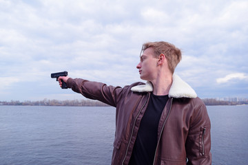 A young guy in a jacket shoots towards the river in nature.