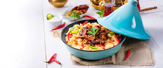 Tajin with couscous, vegetables and meat on white background