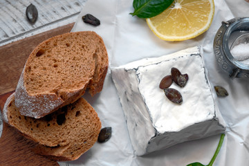 Cheese with brown bread and lemon on wood 