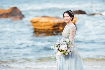 Fototapeta na wymiar bride with a bouquet of flowers on the beach