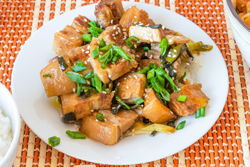 Fried pork belly in sweet and sour sauce in a plate, top view - a traditional Korean dish