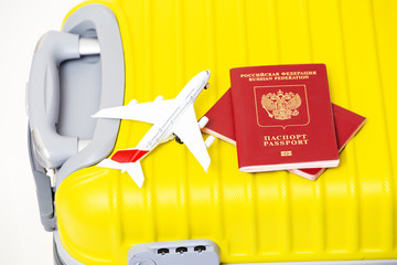 Airplane toy with two Russian Federation passports on a yellow suitcase. Travel and airport custom concept