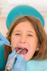 Macro close up of young child with open mouth at dentist. Teeth checkup at dentist's office. Dentist examining girls teeth in the dentists chair. vertical photo