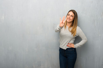 Young woman on textured wall happy and counting four with fingers