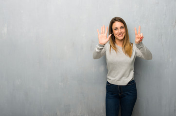 Young woman on textured wall counting seven with fingers