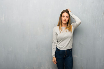 Young woman on textured wall with an expression of frustration and not understanding