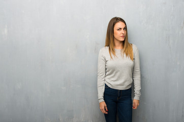 Young woman on textured wall feeling upset