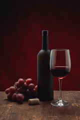 bottle of wine and grapes on wooden background