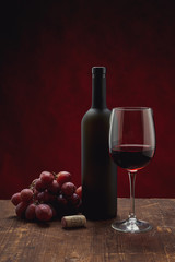 bottle of wine and grapes on wooden background