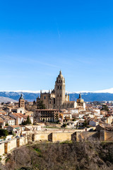 Fototapeta na wymiar Segovia, Spain – View from Juan II tower in Winter time of the Alcazar of the old town of Segovia and the Cathedral with the snow capped Sierra de Guadarrama behind